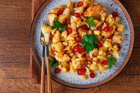 Spicy fried cauliflower served on a wooden countertop