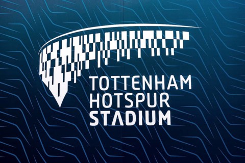 A backlit sign displays the Tottenham Hotspur Stadium name and stylised crest pattern at the