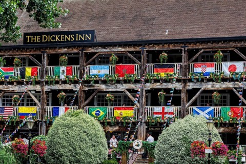 Rows of national flags and hanging flower baskets line the tiered wooden balconies of The Dickens