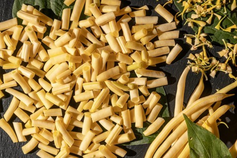 Fresh yellow beans with sliced pieces on a dark background