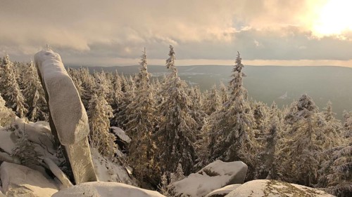 Snowy landscape with rocks, sunlight illuminates the trees and the horizon, Fichtelgebirge nature