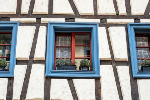 Detailed view of a half-timbered house with blue window frames and flower decoration in the old