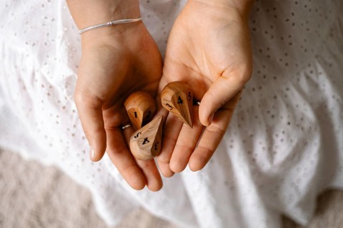 Hands holding wooden dice with numbers in a simple, natural setting
