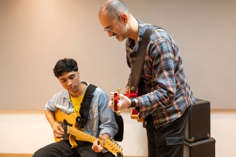 Two musicians collaborate in a recording studio, focusing on guitar techniques. The scene captures