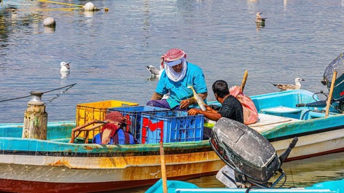 Fishermen working on their boats in the harbour of Mirbat, Dhofar Province, Arabian Peninsula,