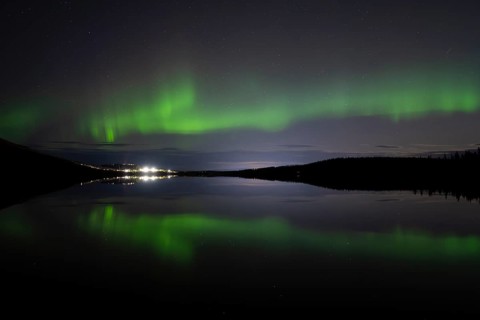 The Northern Lights (Aurora borealis) reflected in a forest lake, Gällivare, Norrbotten, Lapland,