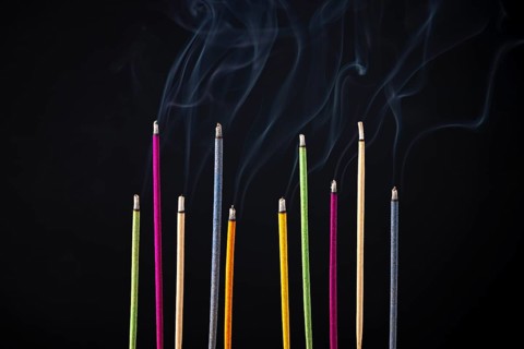 Colourful smoking incense sticks on black background