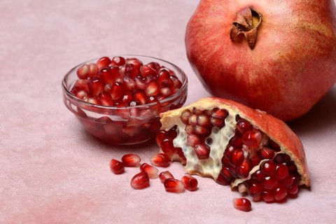 Opened pomegranate and pomegranate seeds in skin, Punica granatum
