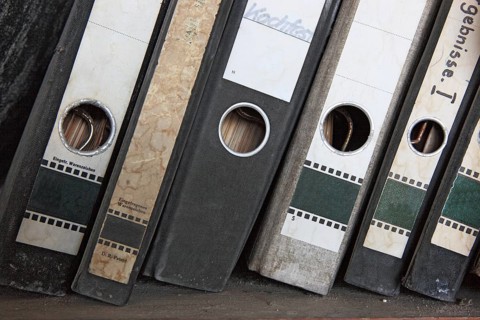Office scene around 1982, lost place, abandoned location, classic file folders on a wooden shelf,