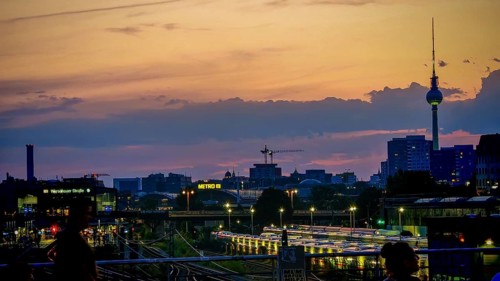 View of railway tracks from Modersohn Bridge, skyline at dusk with television tower and illuminated