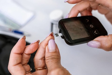 Macro view of inserting a blood glucose test strip into a digital glucose meter. Diabetes