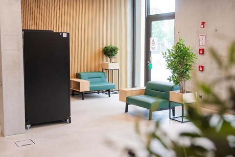 Inviting modern seating area with green sofas and wooden wall, Boarding House des Klinikverbund