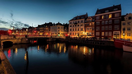 Stimmungsvolle Abendaufnahme eines Kanals mit beleuchteten, alten Gebäuden, Kopenhagen, Dänemark,