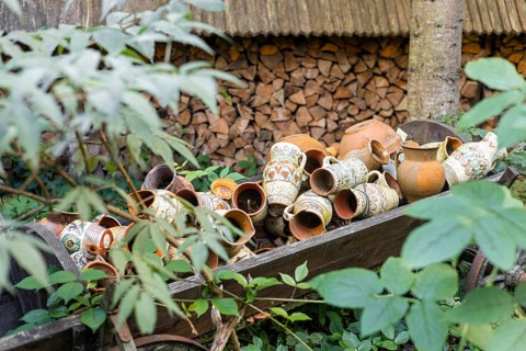 A collection of traditional clay pots in various sizes and designs, resting on a wooden cart