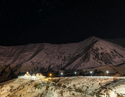 Amaglebis eklesia orthodox church complex at night surounded by mountains and stars in the