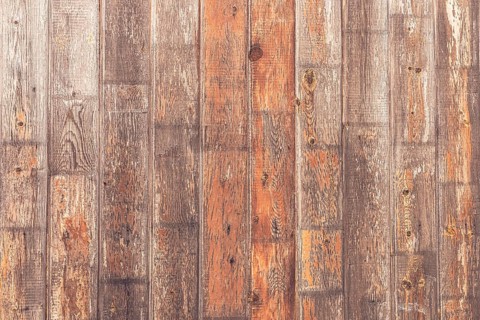 A close-up view of a rustic wooden wall with various shades of brown and gray. The planks show