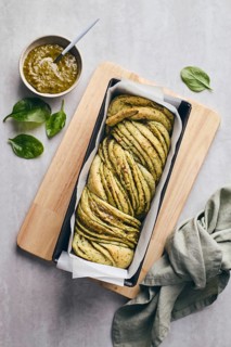 Baked homemade savoury babka plaited bread loaf flavoured with cheese and pesto, in the making tin