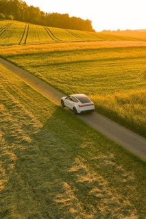 A car drives on a road through golden fields and enjoys dusk, Tesla Model Y, Gechingen, Calw