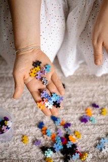Outstretched hand with colorful puzzle pieces, suggesting creativity and play