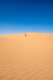 Lonely person photographing on a sand dune, sand dunes with wave patterns, sea of dunes, sandy