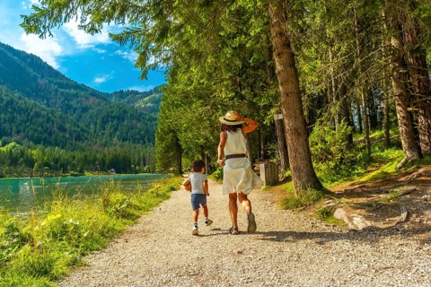 Mother and son running on a path along the shore of lake dobbiaco enjoying the tranquility of the