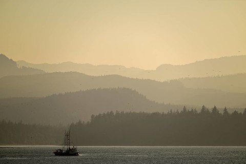 Foggy, romantic sunset mood at the Pacific Ocean with fishing boat in the foreground, Vancouver