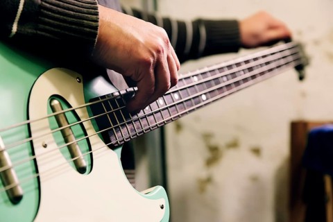 A skilled luthier works on a bass guitar in a well-equipped workshop, highlighting precision and