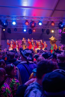 A lively concert with red lights in front of an enthusiastic crowd in the party tent, carnival,