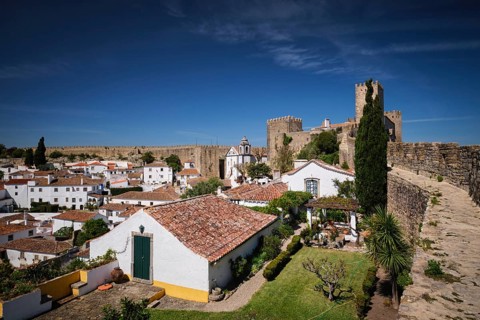 Obidos features a stunning medieval castle overlooking quaint white houses and rooftops in a