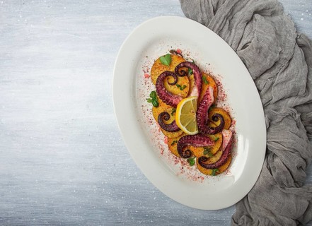 Octopus with potatoes and spices, on a light plate, top view, no people, homemade, close-up