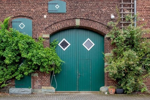 Green barn door in a brick façade, rural atmosphere, Germany