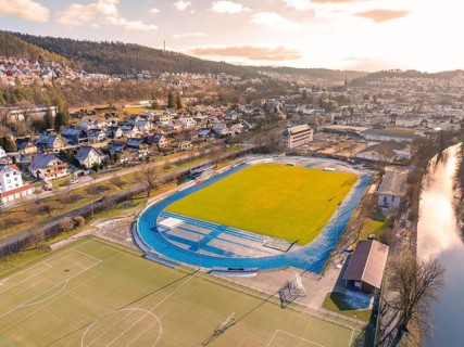 Green sports facility with houses in the background, enveloped by hills in daylight, Nagold, Black