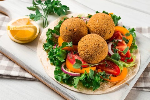 Tortillas, wrapped falafel balls, with fresh vegetables, vegetarian healthy food, on a wooden white