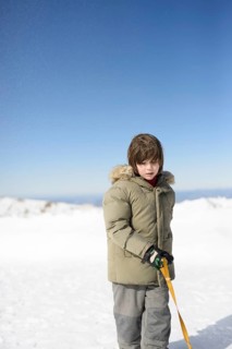 A young child in a winter coat stands amidst the snow at Sierra Nevada Ski Resort, Granada. The