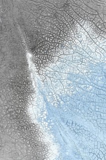 Close-up of an abstract icy surface featuring intricate crack patterns in shades of gray and blue,