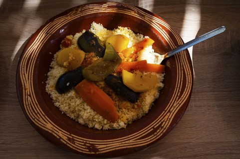 Traditional Moroccan dish of couscous and vegetables, on a plate, lit by the sun, Morocco