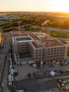 Constructed building and construction site with cranes in an urban environment at sunset, new