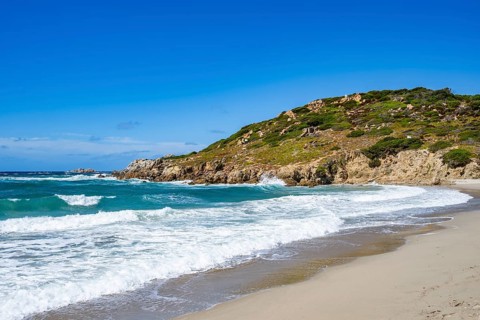 Coastline with emerald green and blue water on a sunny day at Rena Majori beach, Sardinia, Italy