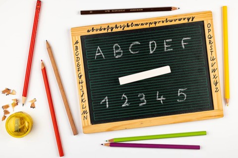 School blackboard with letters, numbers and chalk, pencils and sharpener next to it