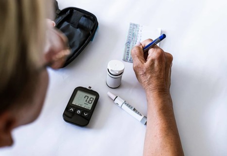 Woman recording blood glucose results after diabetes testing at home. Self-monitoring, glycemic