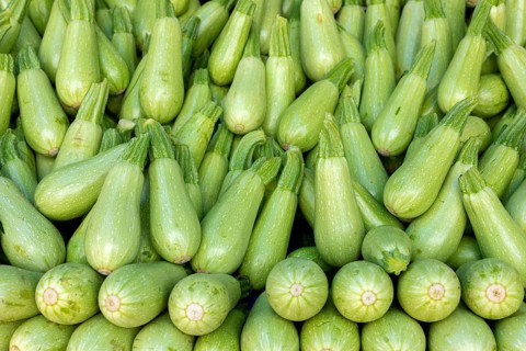 A neatly stacked pyramid of light green squash displayed at a market