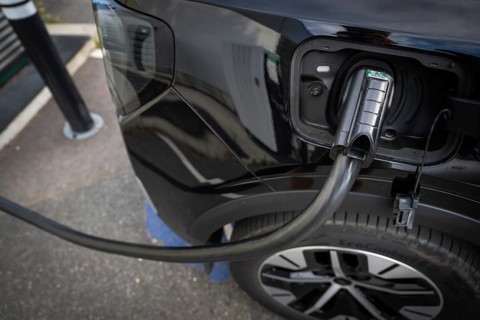 Fully electric Ford Explorer is being charged, charging cable in electric tank, charging station