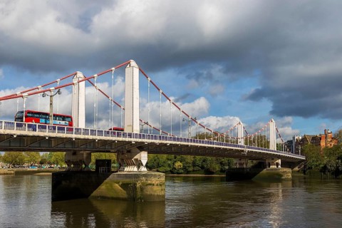 A red double decker bus crosses the 1937 Chelsea Bridge over the River Thames, London, England,