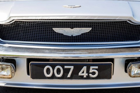 Aston Martin wing badge above a novelty 007 registration plate on a classic car