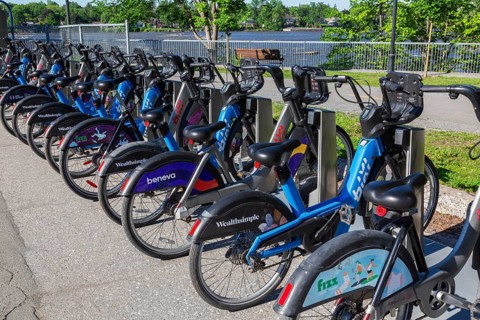 Parked electric and standard Bixi ride sharing bikes with company sponsor logos on rear wheel