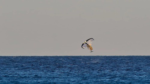 Wingfoiller, daring kitesurfer over the ocean waves, windsurfer, Meltemi windsurfing spot, Devils