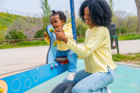 Three quarter length photo of an african mother and little girl playing in the playground