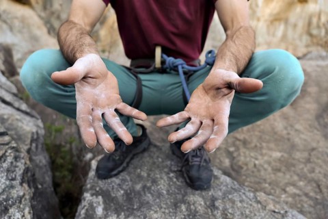 Close-up of a climber's hands showing the strength needed for rock climbing. The image highlights