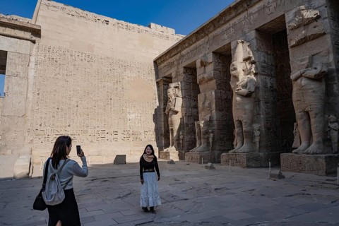 Foreign tourists admire the reliefs and hieroglyphs inside Medinat Habu, the ancient Egyptian