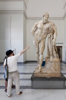 Museum visitors in front of Hercules Farnese, monumental marble statue by sculptor Gykon, Farnese